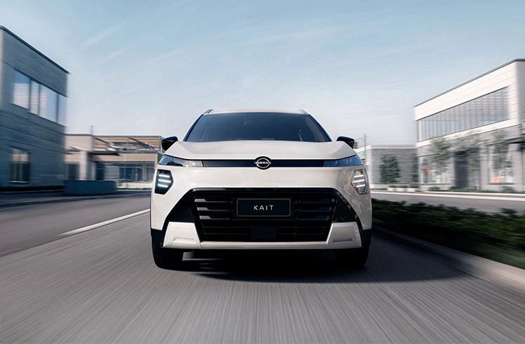 SUV Nissan KAIT branco visto de frente em movimento rápido em uma rua urbana. O fundo da cidade está borrado, indicando velocidade.